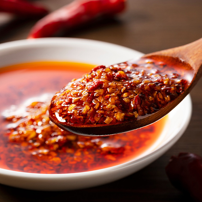 Chilis in oil being spooned out of a bowl