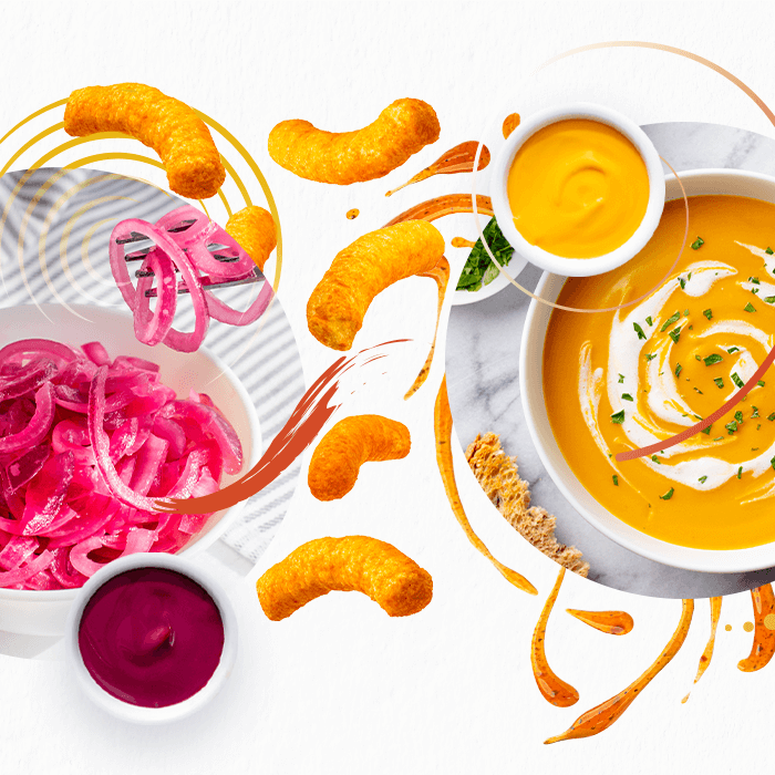 Colorful foods including orange puffed snacks, yellow soup &amp; sauce, and red sauce