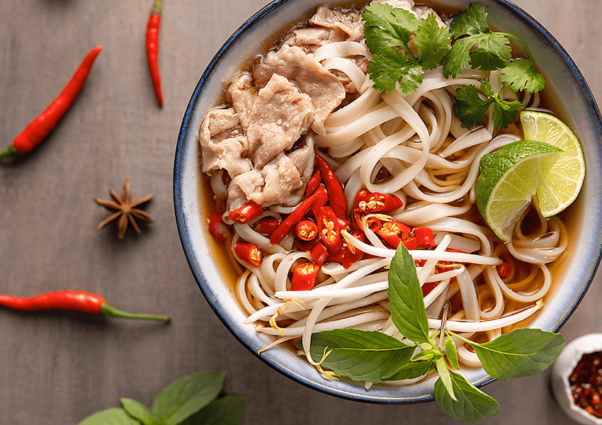 Bowl of pho garnished with herbs