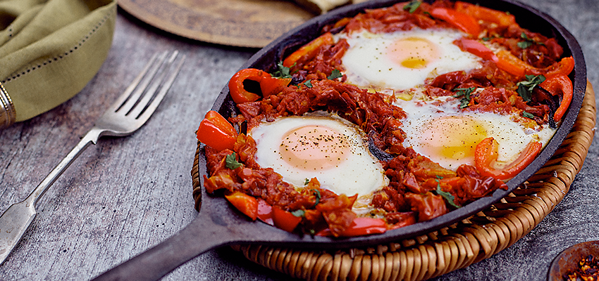 Cast iron skillet of eggs, peppers and tomatoes