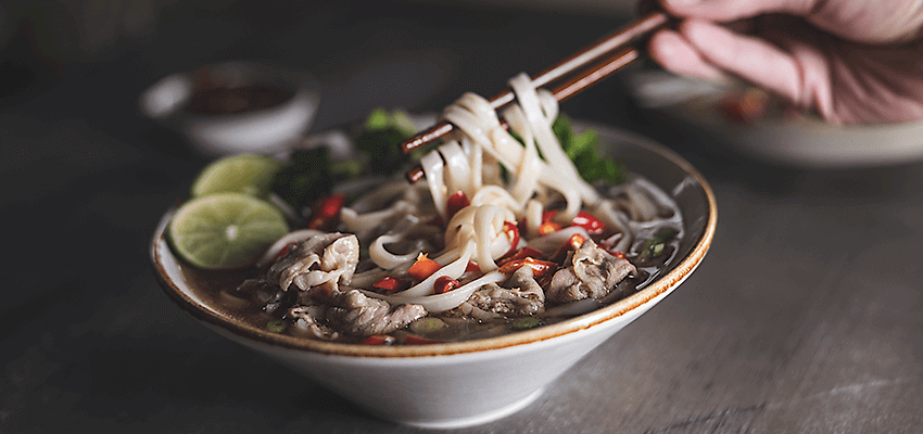 Noodle bowl with lime slices and chopped red pepper