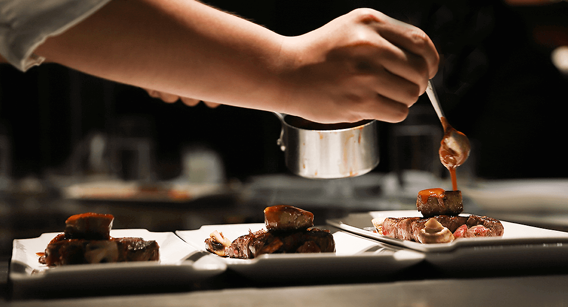 Chef adding sauce onto a plated dish