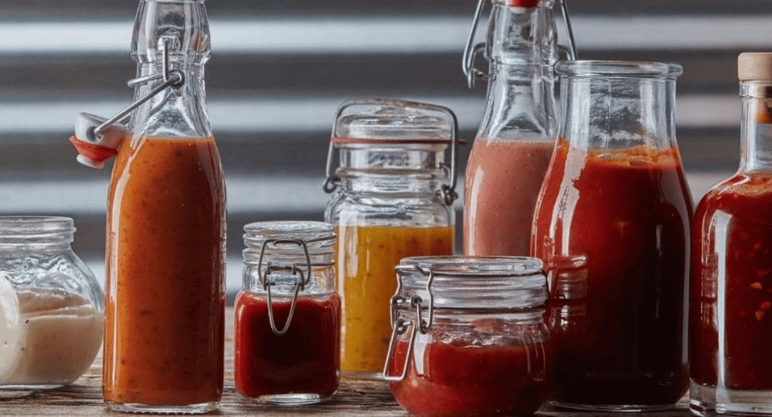 Glass jars filled with hot sauces and peppers